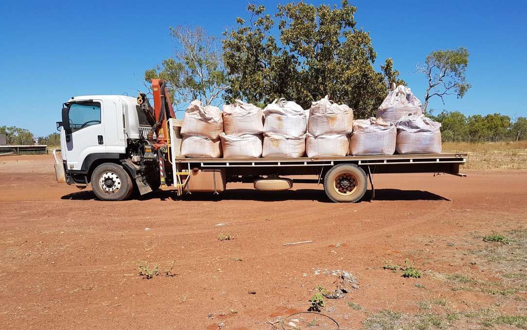 A White Truck With A Crane On The Back Is Parked In A Dirt Field — Territory Industries Pty Ltd In Timber Creek, NT