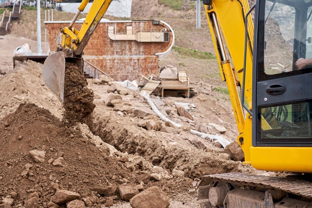 A Yellow Excavator Is Digging A Hole In The Ground — Territory Industries Pty Ltd In Timber Creek, NT