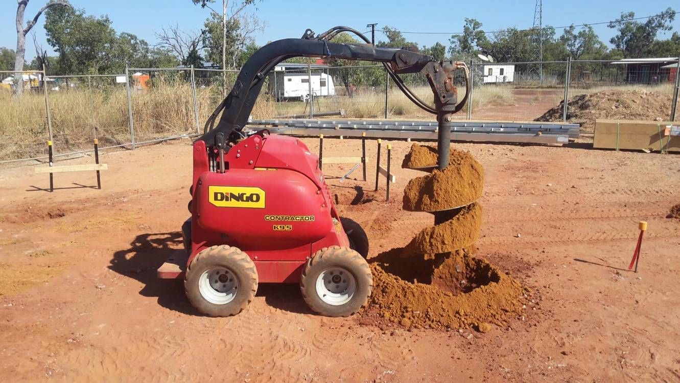 A Red Tractor Is Digging A Hole In The Dirt — Territory Industries Pty Ltd In Uralla, NT