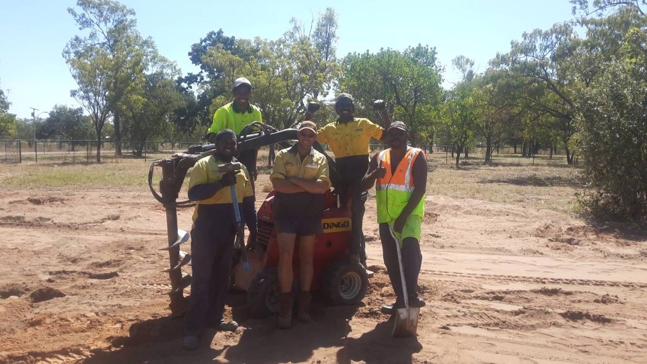 A Group Of People Are Posing For A Picture In A Dirt Field — Territory Industries Pty Ltd In Uralla, NT