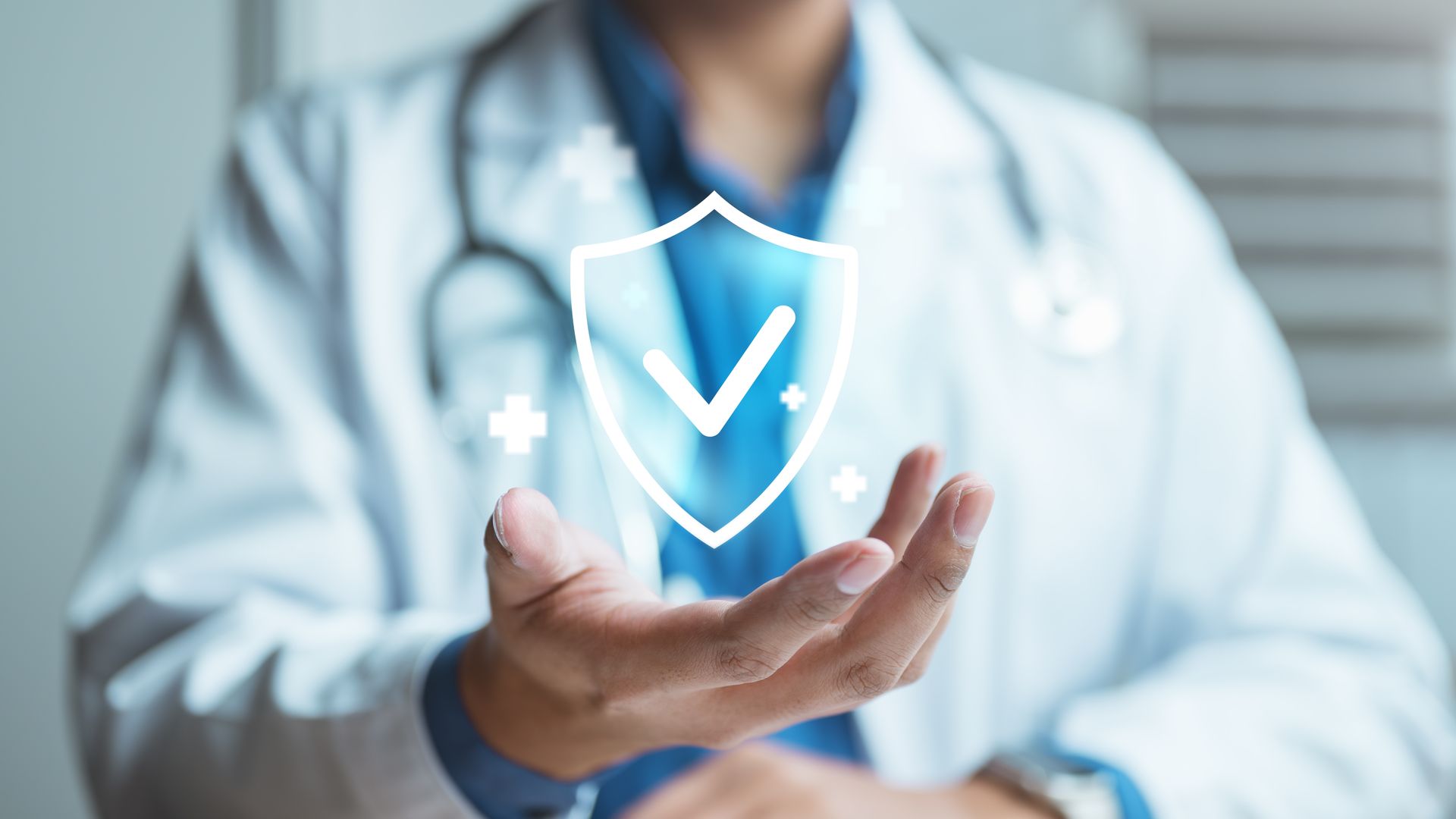 A doctor holds a digital, glowing shield icon with a checkmark, symbolizing health protection and medical security.