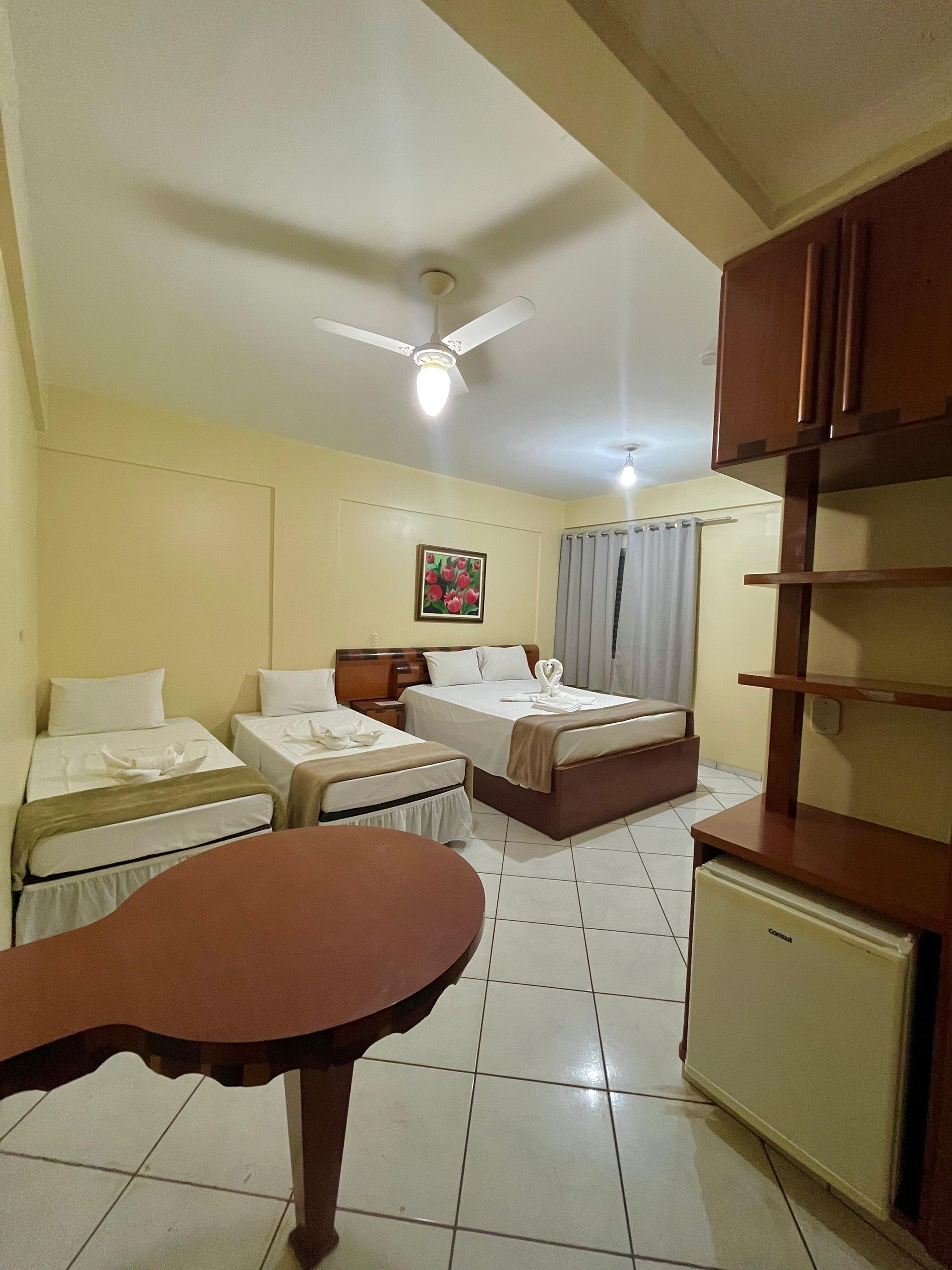 Um quarto de hotel com três camas e uma mesa