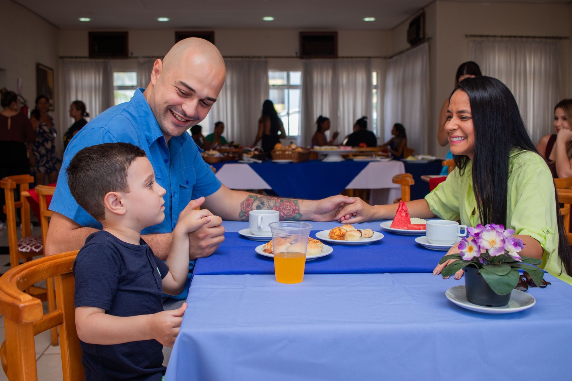 Um homem, uma mulher e uma criança estão sentados à mesa em um restaurante.