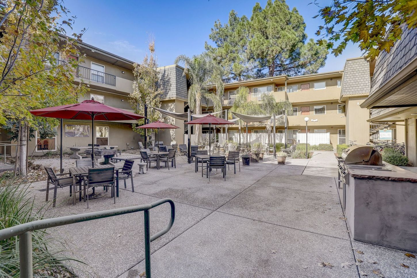 A courtyard with tables and chairs and umbrellas in front of a building.