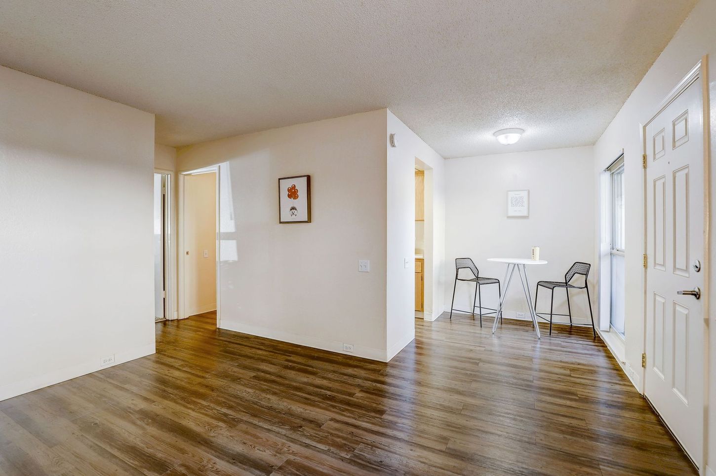 A living room with hardwood floors and a table and chairs.