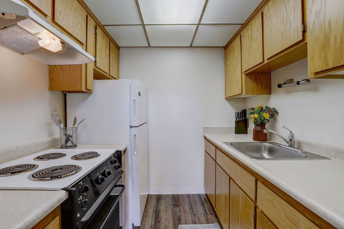 A kitchen with a stove , refrigerator , sink and cabinets