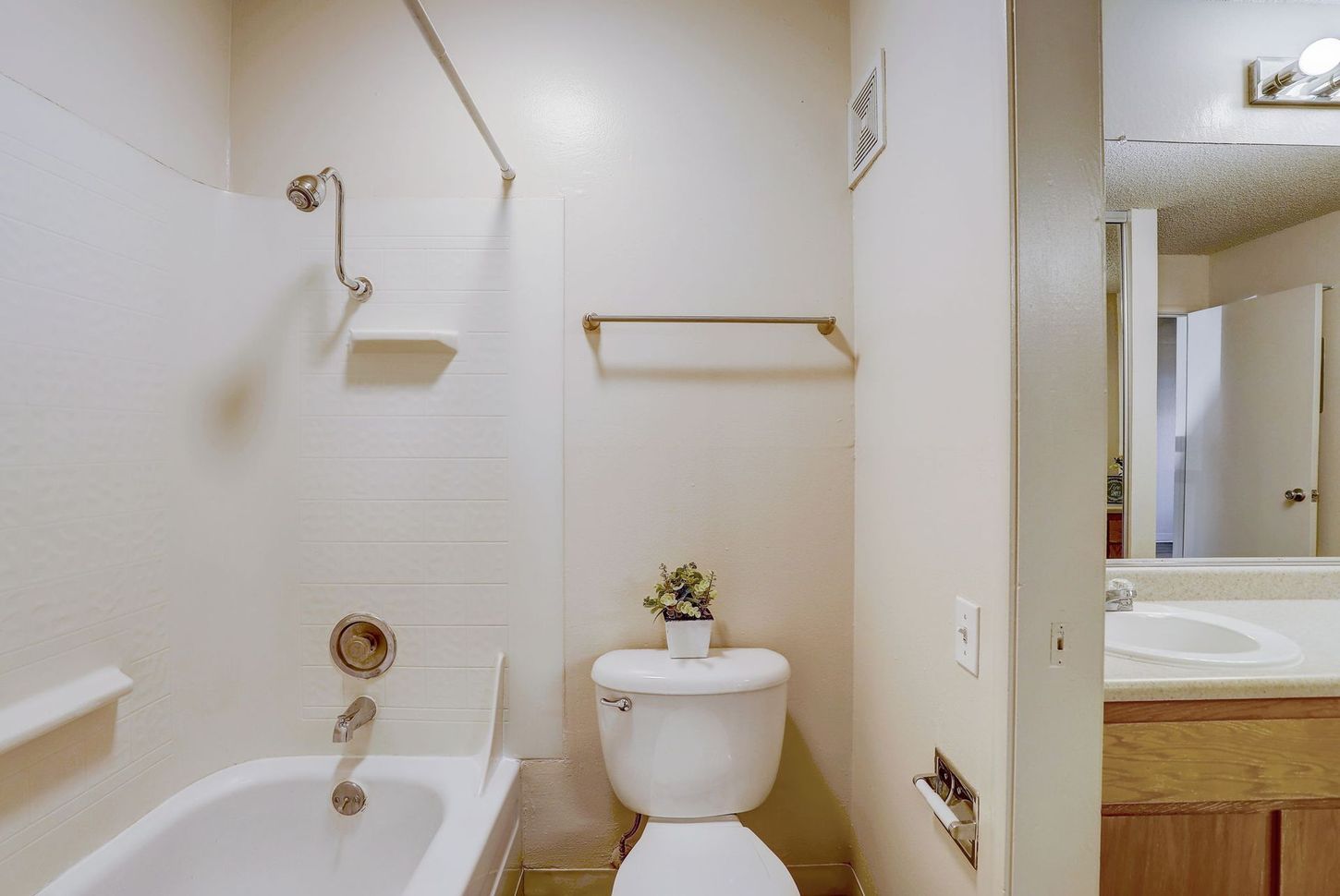 A bathroom with a toilet , bathtub , sink and mirror.