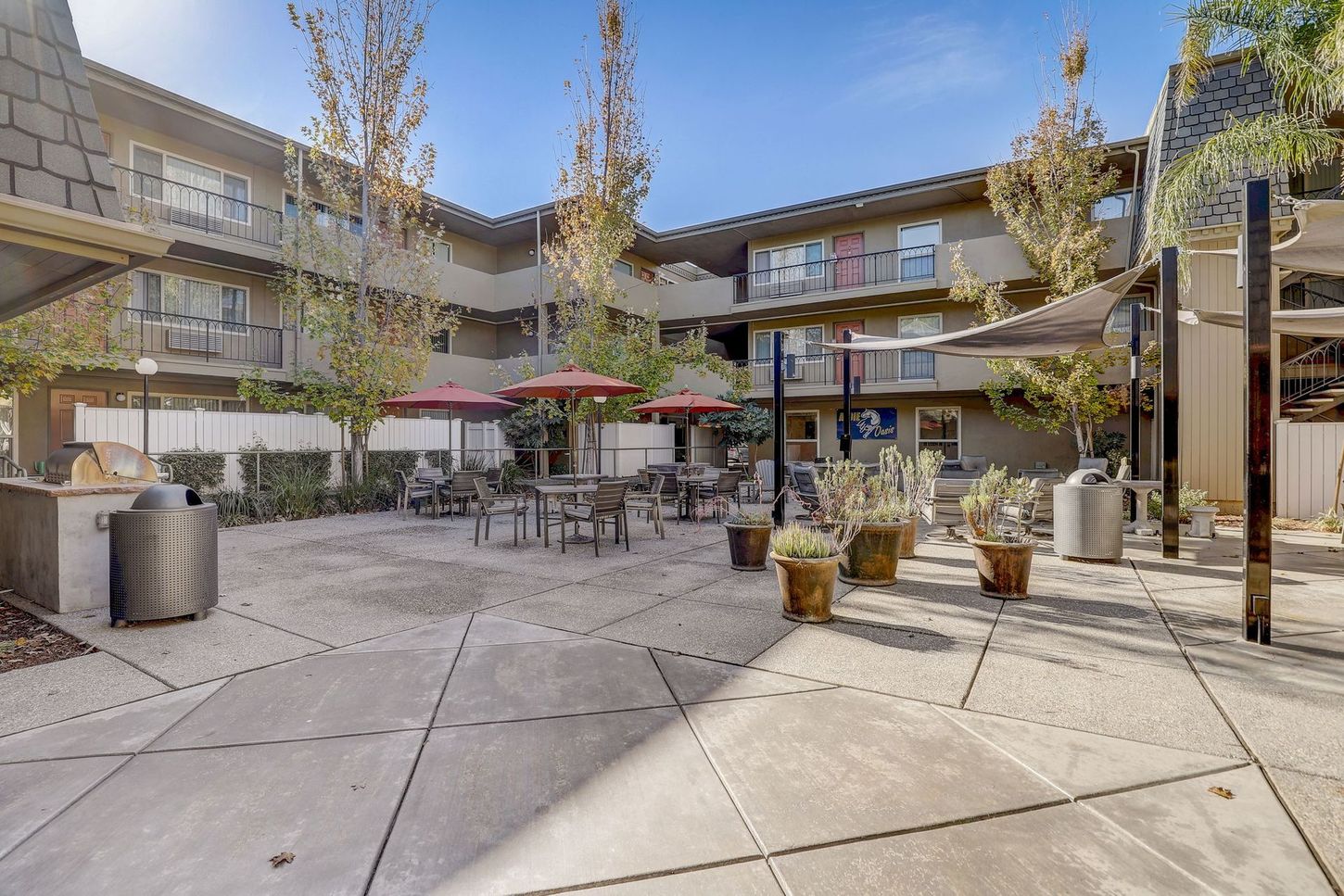 A courtyard with tables and chairs and umbrellas in front of a building.