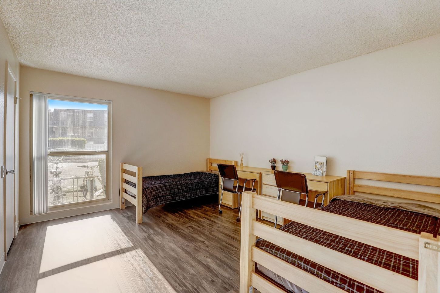 A bedroom with two beds , a desk and a window.