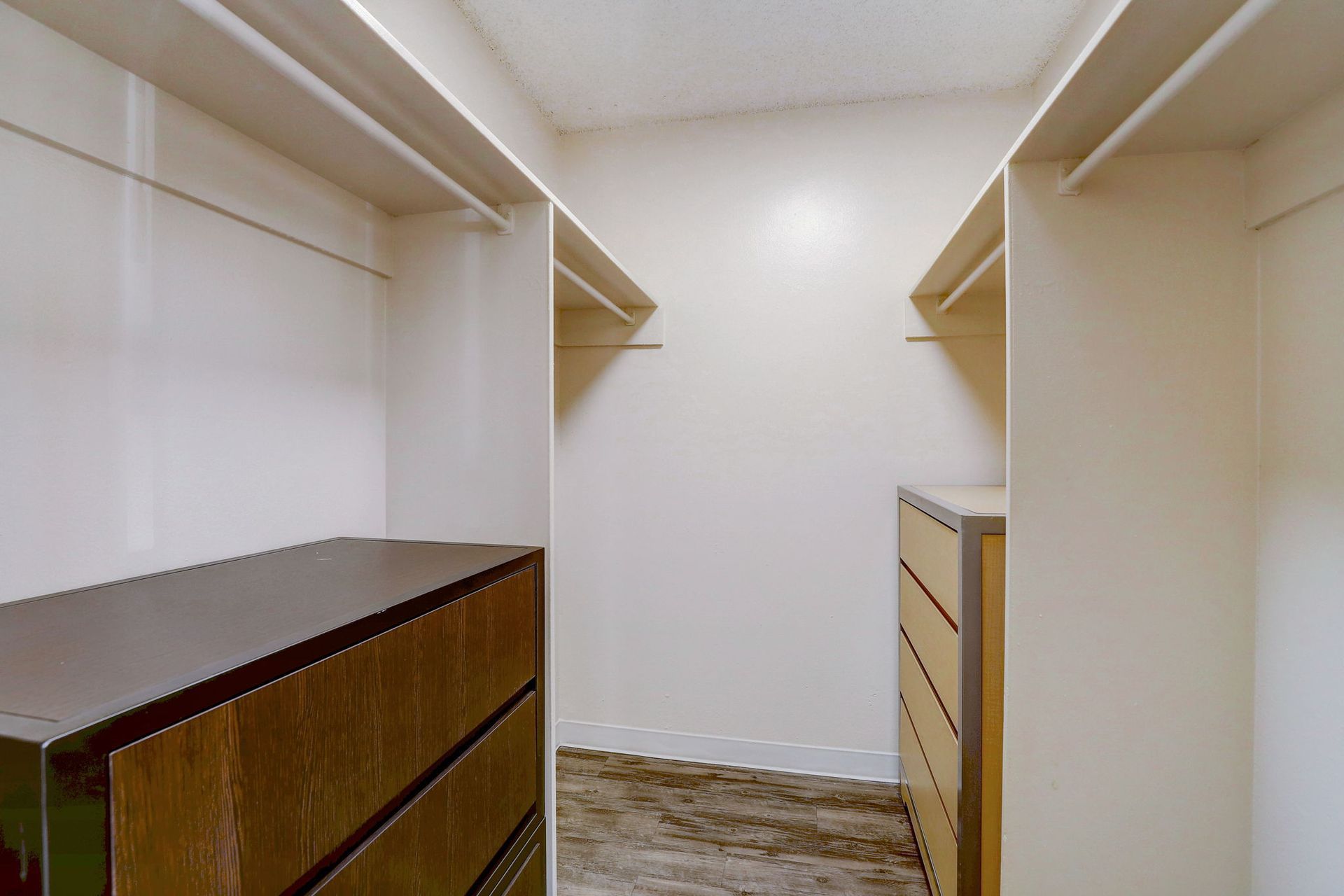 A walk in closet with a dresser and shelves