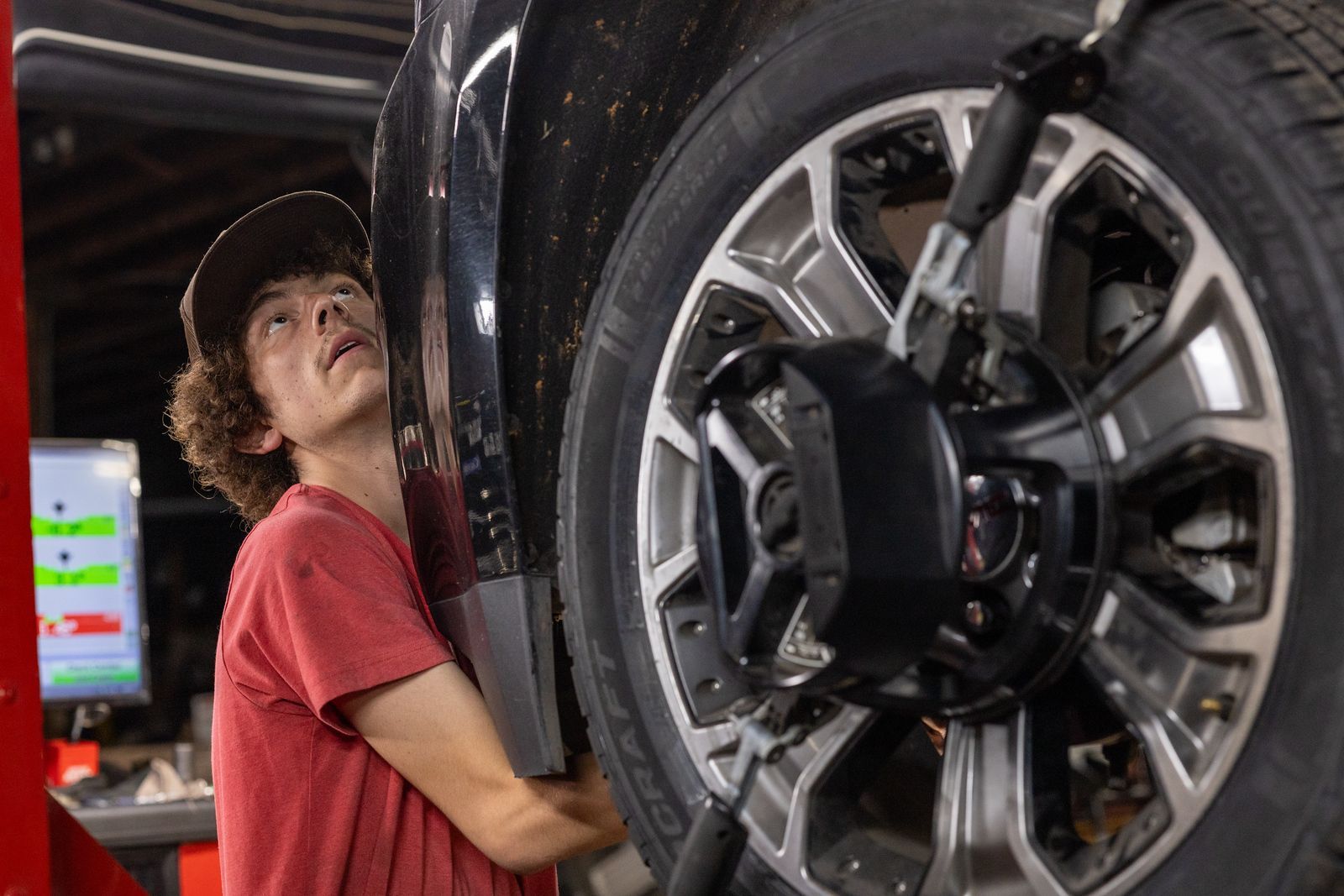 A service mechanic is adjusting a tire on a lift in a garage.