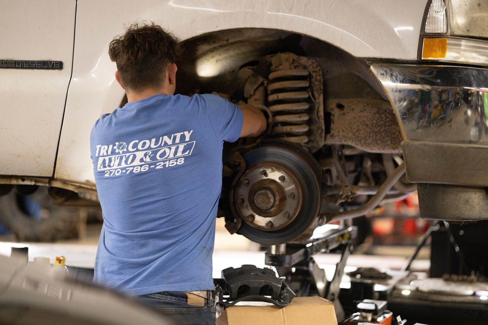A service mechanic is working on a car in a garage.