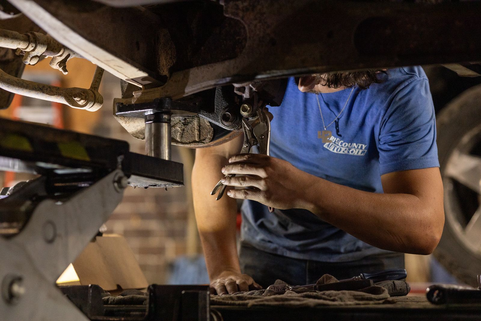 A service mechanic is working on a car in a garage.