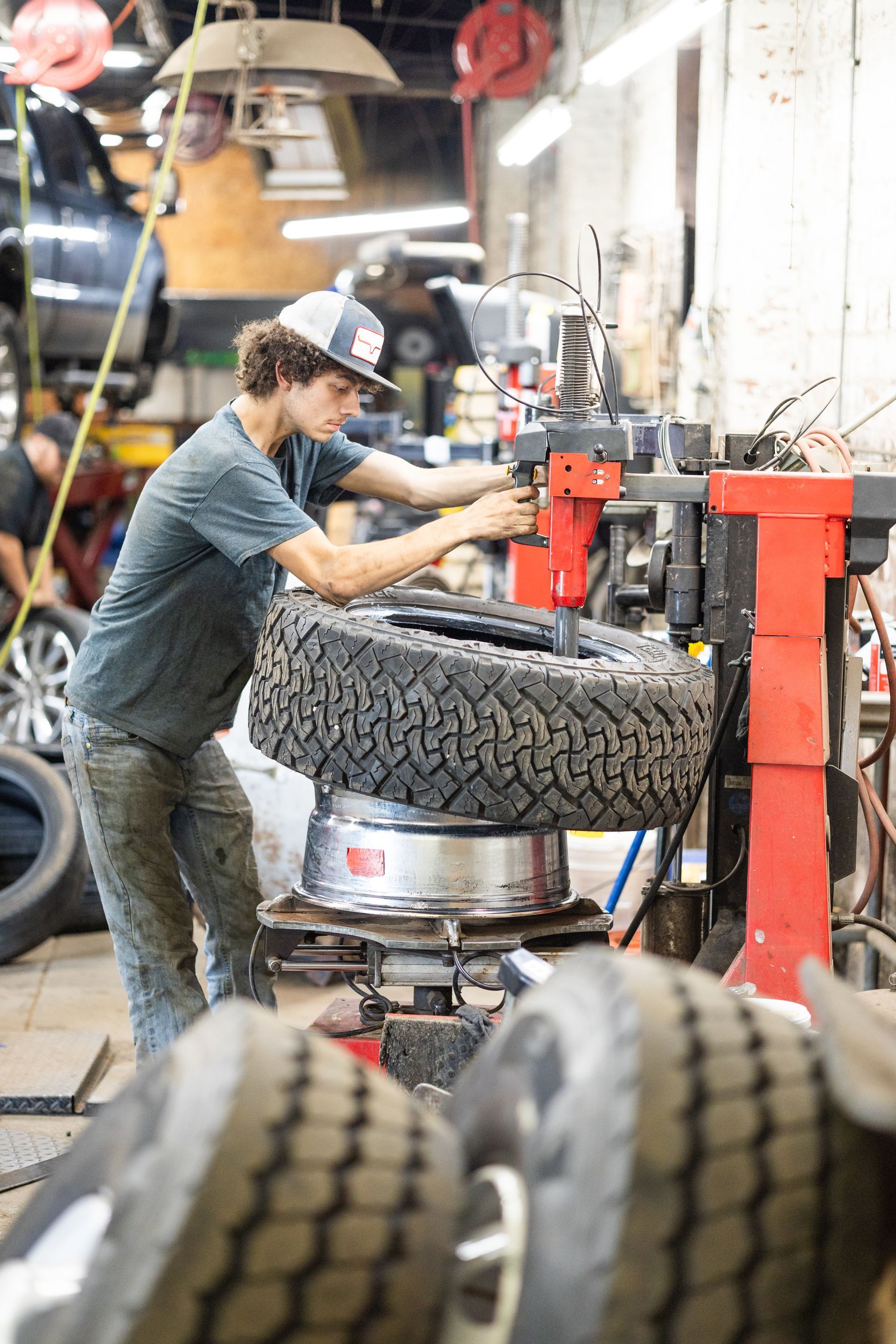 A service mechanic is changing a tire in a garage.