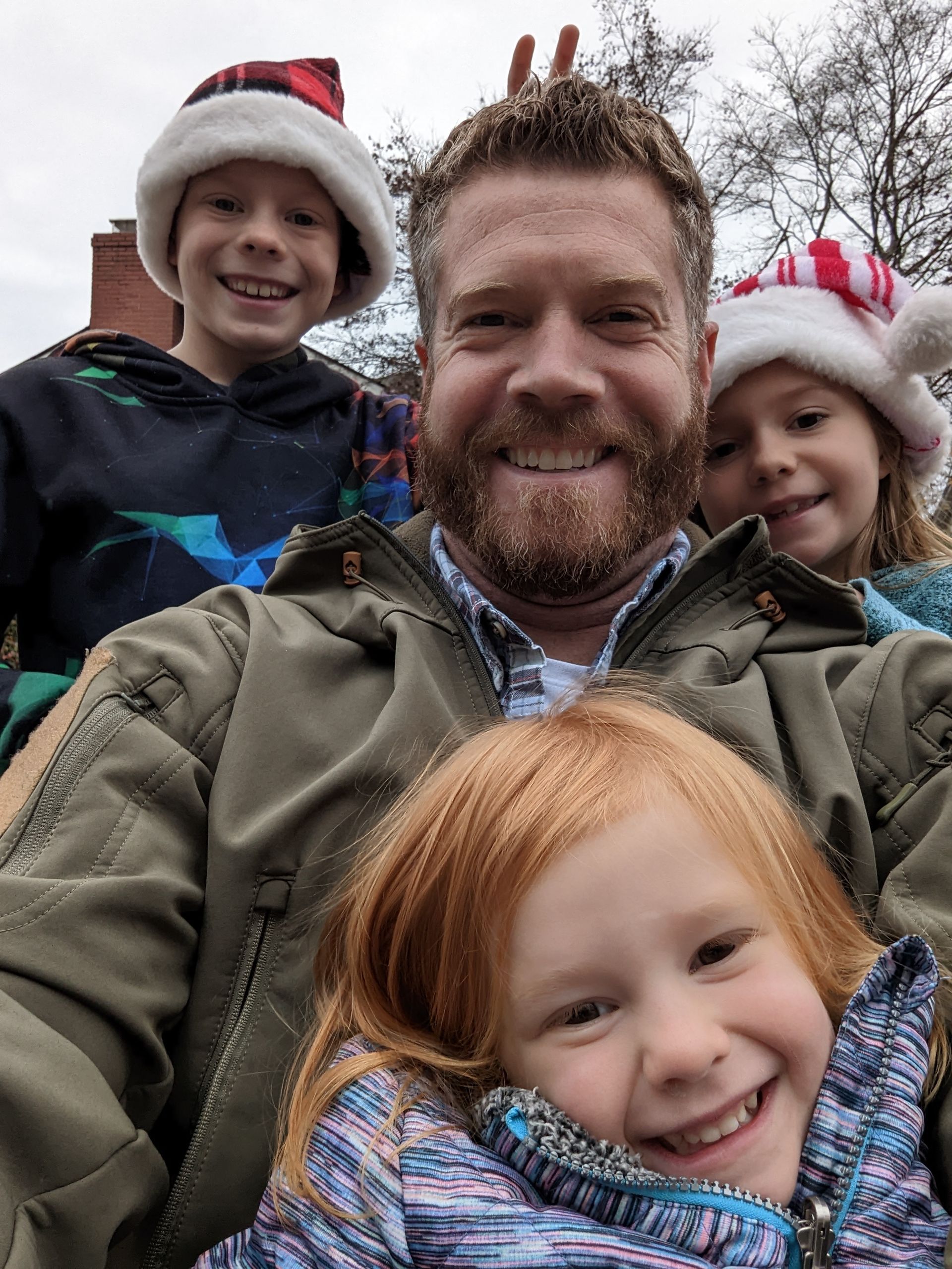 A man is taking a selfie with his three children.
