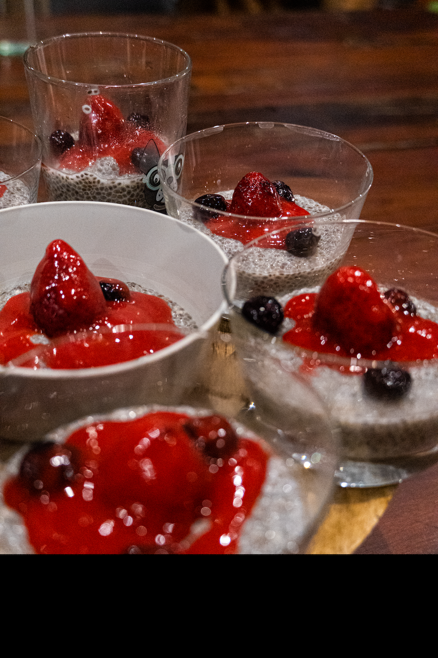 Trois bols de dessert avec fraises et myrtilles sur une table en bois.
