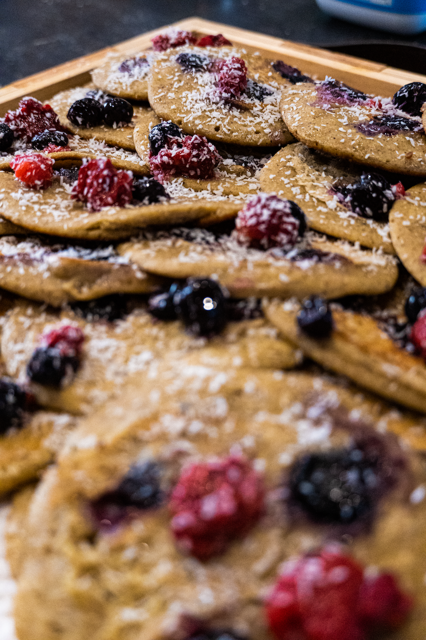 Un plateau de crêpes avec des baies et du sucre en poudre dessus.