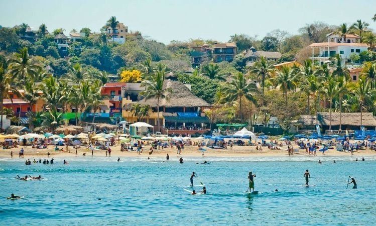 Un groupe de personnes nagent dans l'océan près d'une plage dans Sayulita, le village de la retraite