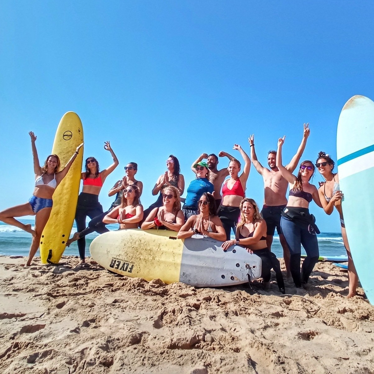 Des Yogis posent pour une photo sur la plage avec leurs planches de surf lors de la retraite au Portugal