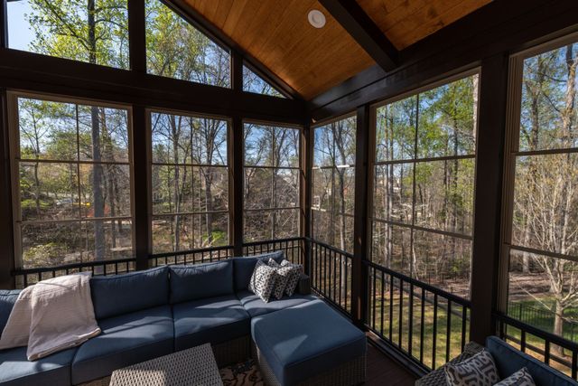 A screened in porch with a blue couch and ottoman.