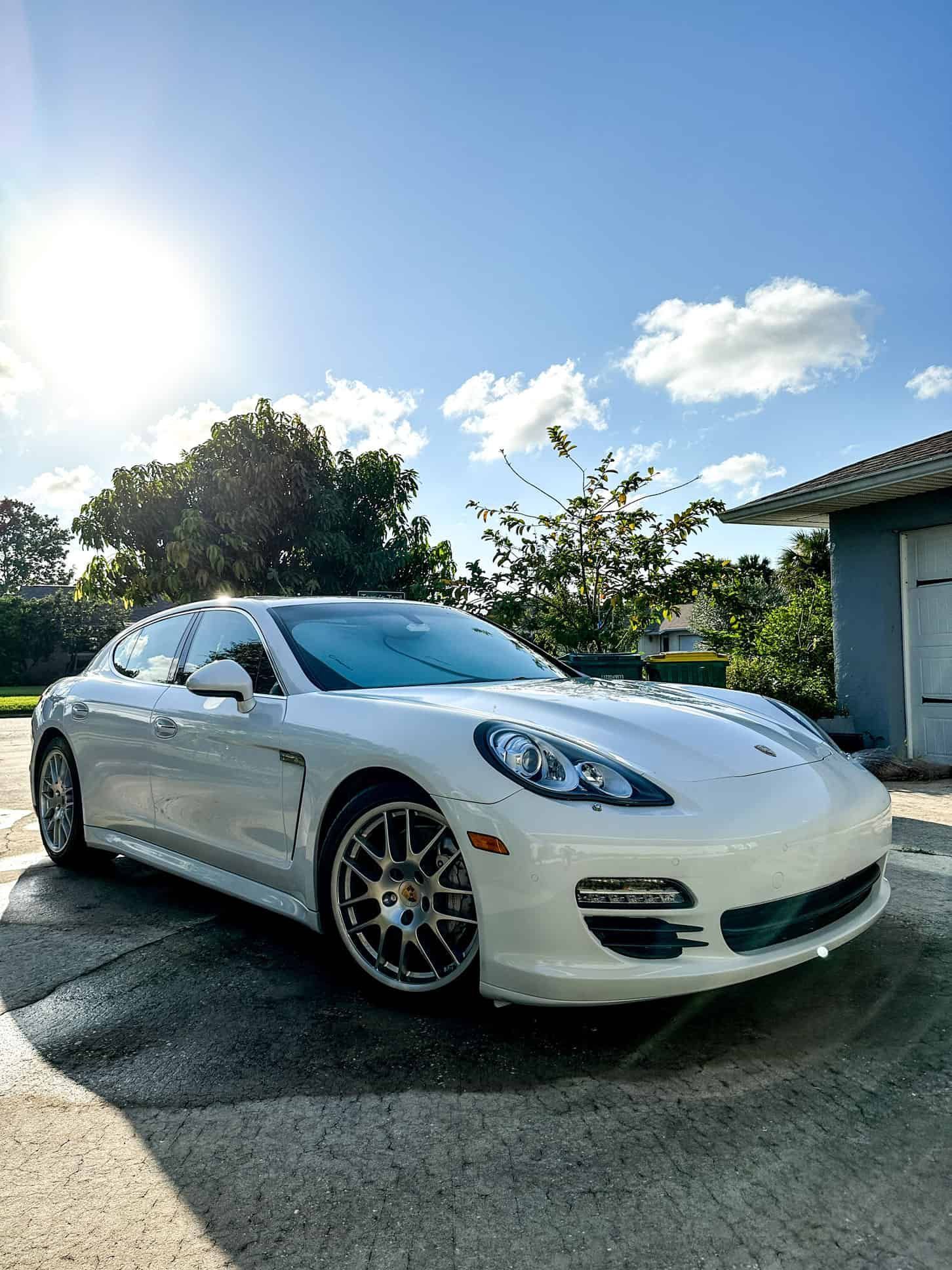 a ceramic coated 2019 White Porsche Panamera with the sun behind it and the wheels slightly turned 
