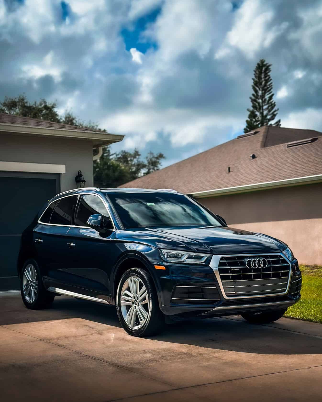 a ceramic coated black 2019 Audi Q5 Prestige with glossy tire shine sitting in front of a grey house in Palm Bay, FL