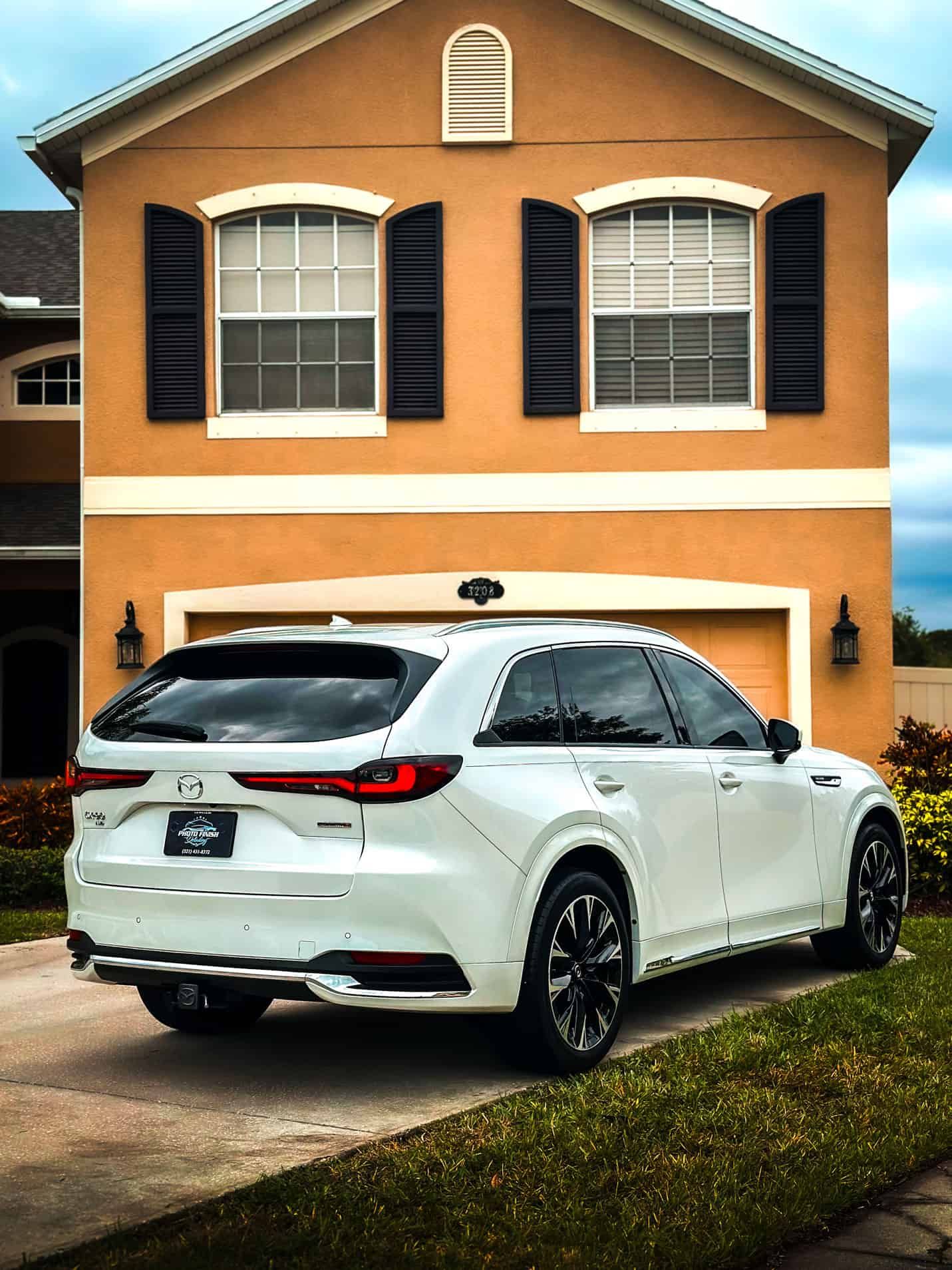 a Ceramic Coated white 2024 Mazda CX-90 3.3 Turbo S Premium Plus in front of an Orange house in Melbourne, FL