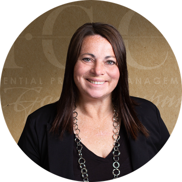 Woman with brown hair smiles, wearing a black blazer and necklace. Brown background with logo.