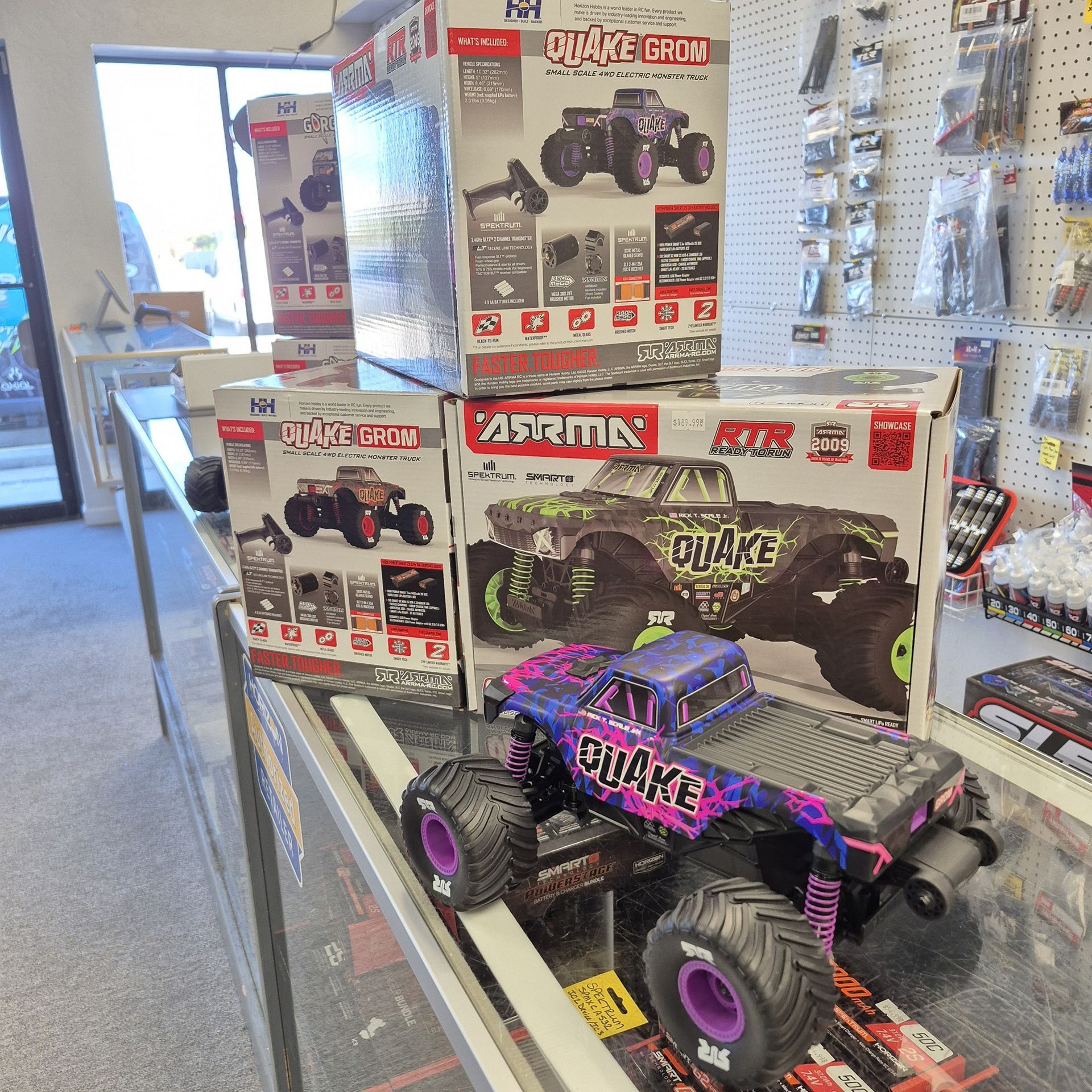 RC monster trucks displayed on a store counter, with boxes of the trucks behind.