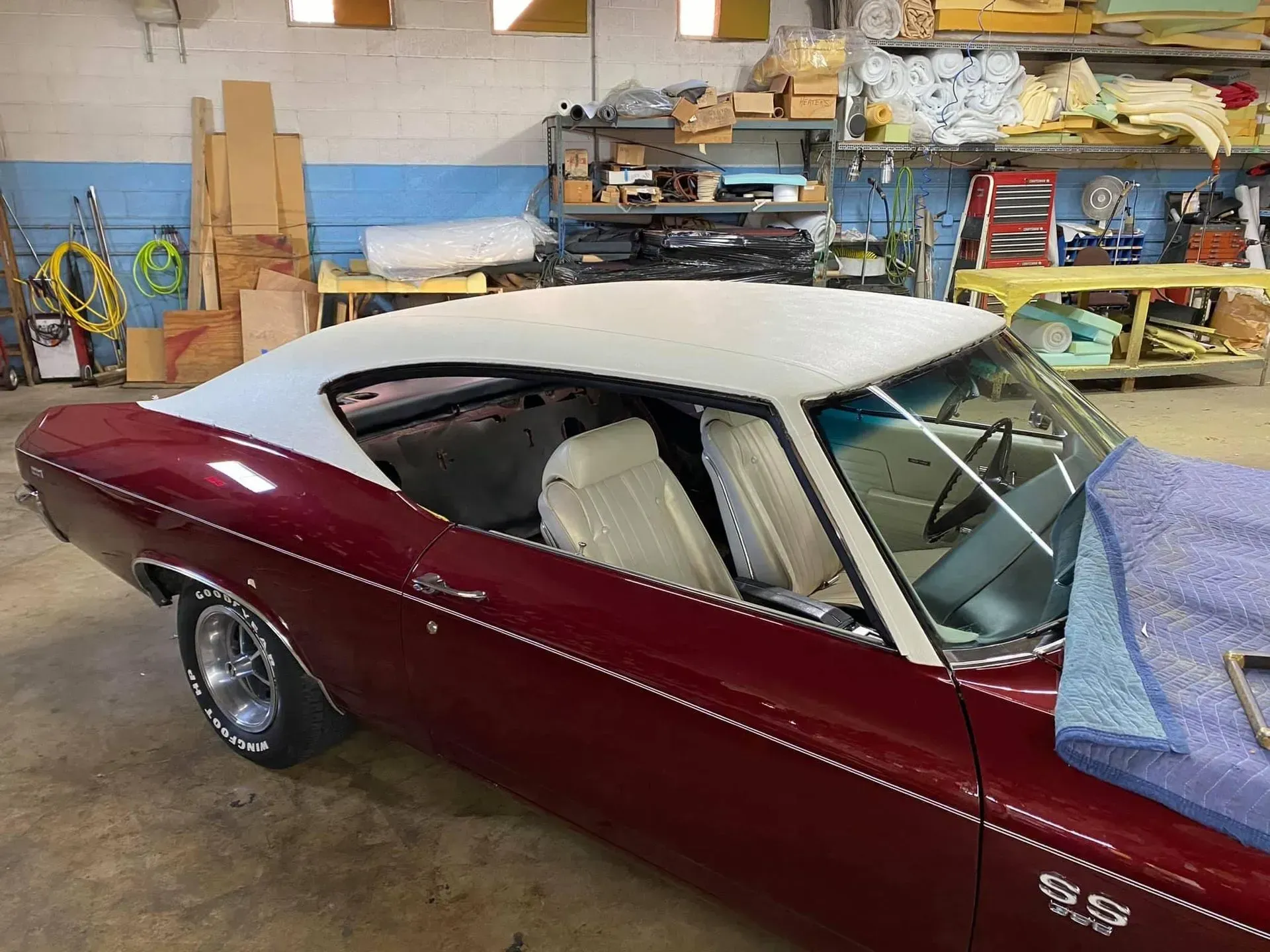 A red car with a white roof is parked in a garage