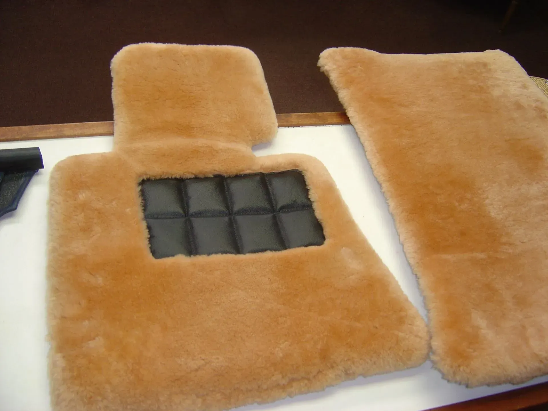 A pair of brown furry floor mats on a table