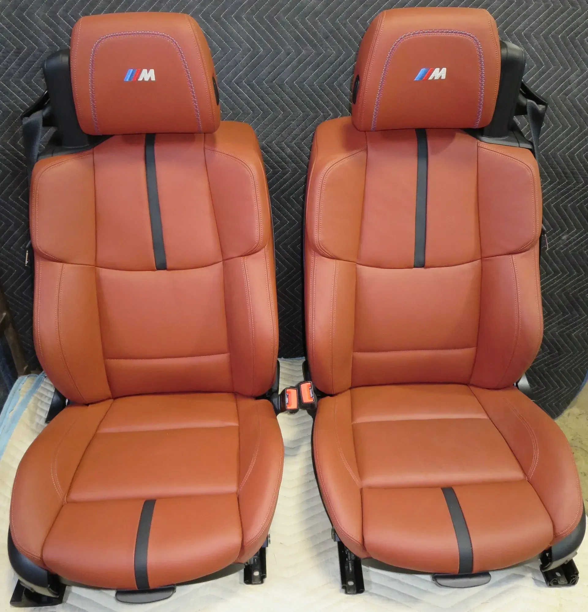 A pair of brown leather seats with the letter m on the headrests