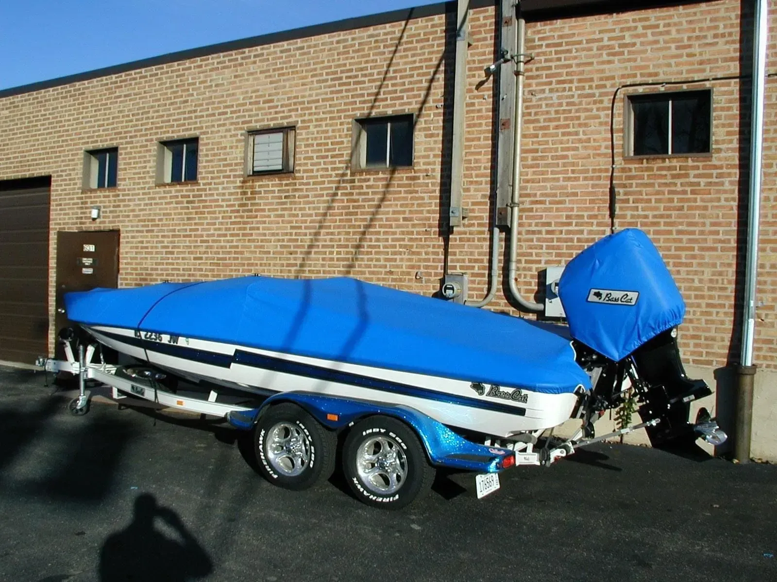 A blue and white boat is parked in front of a brick building