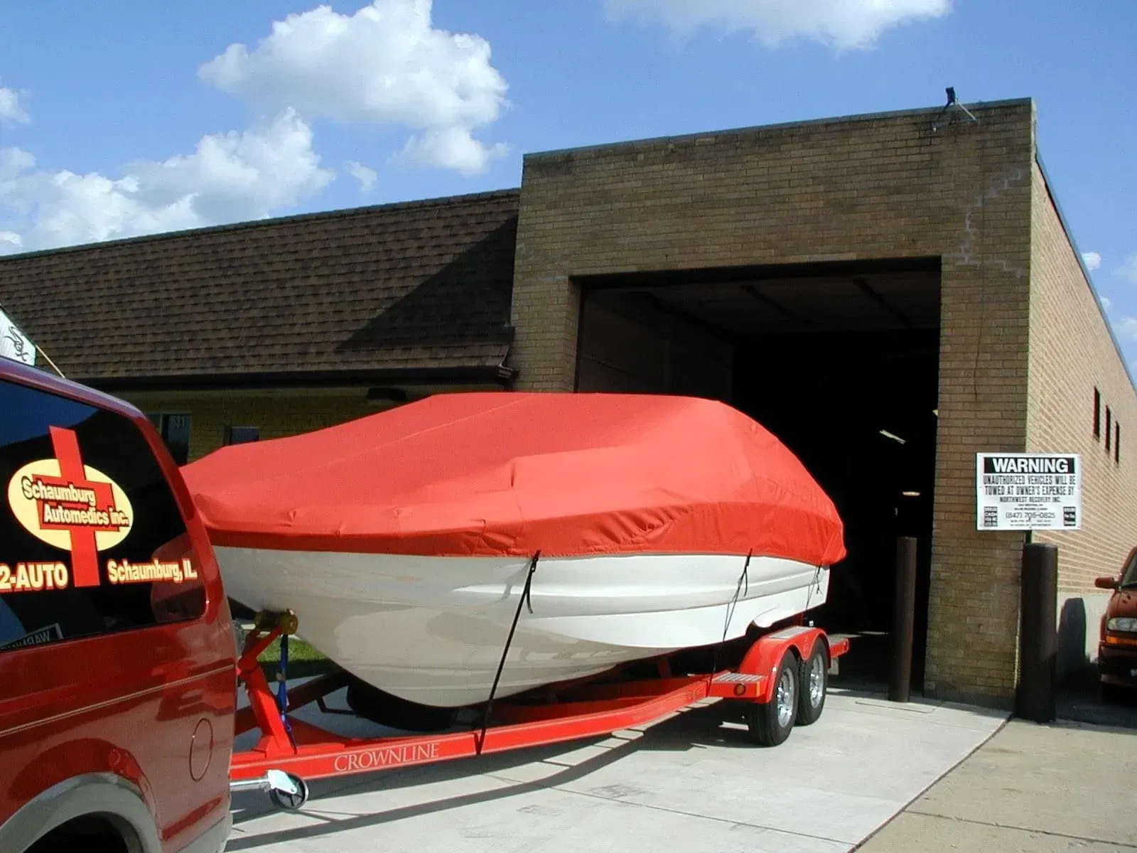 A boat on a trailer is covered in a red cover