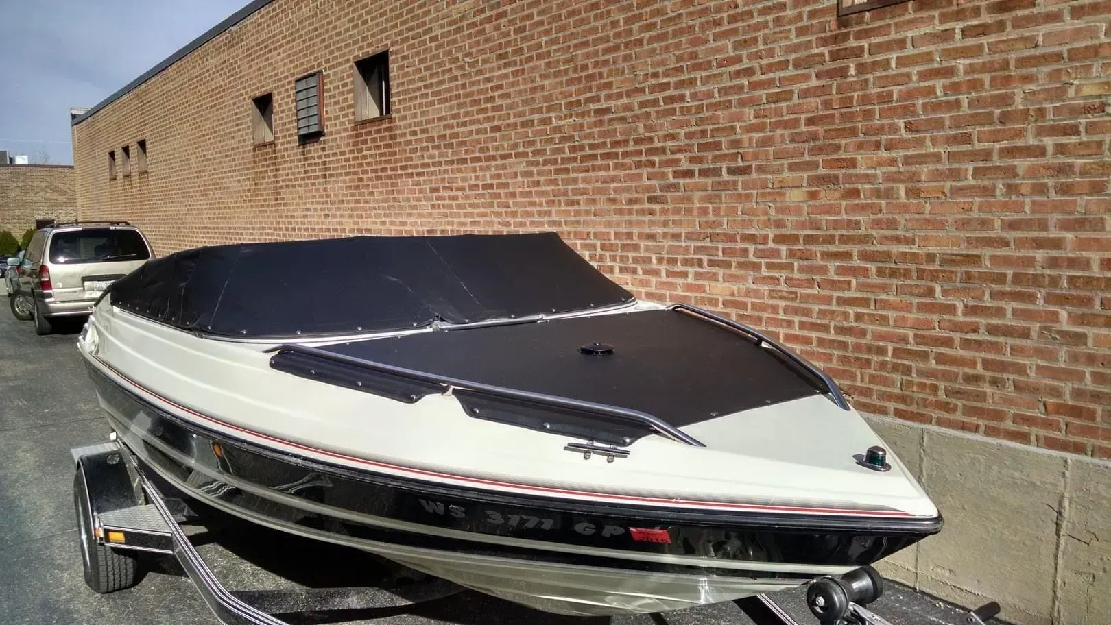 A white and black boat is parked in front of a brick building.
