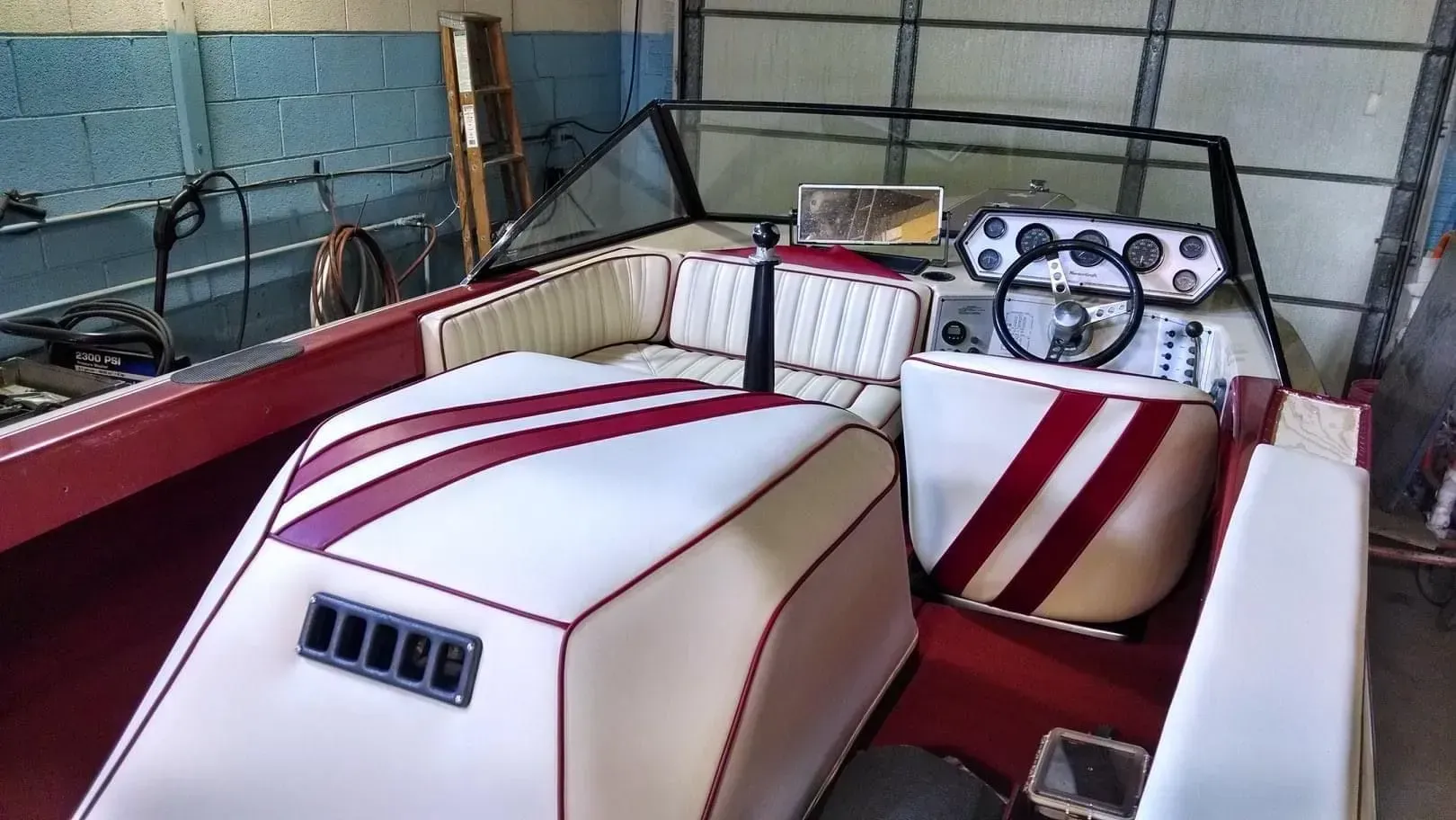 A red and white boat is parked in a garage.