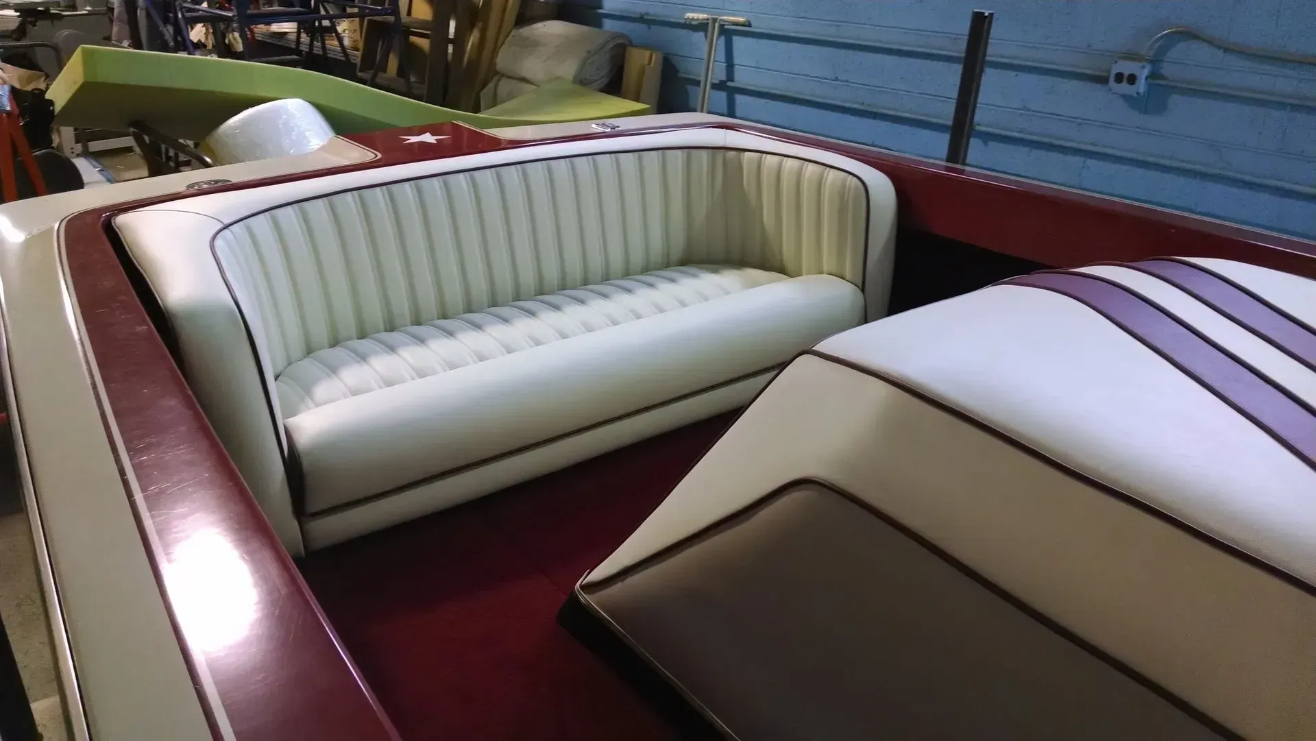 A boat with a white couch and purple stripes