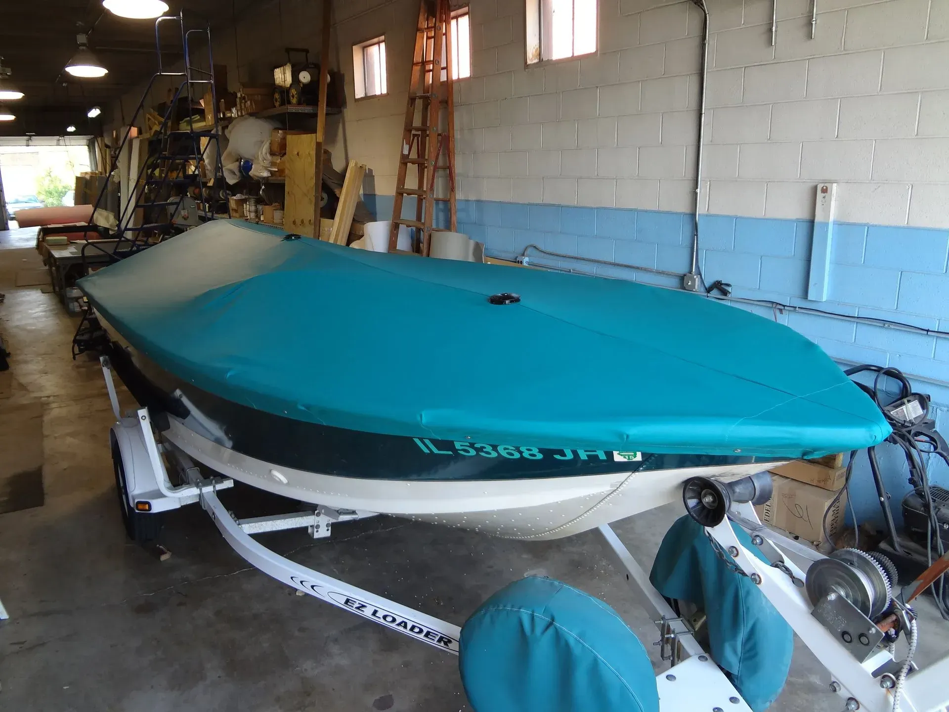 A boat with a blue cover on it is on a trailer