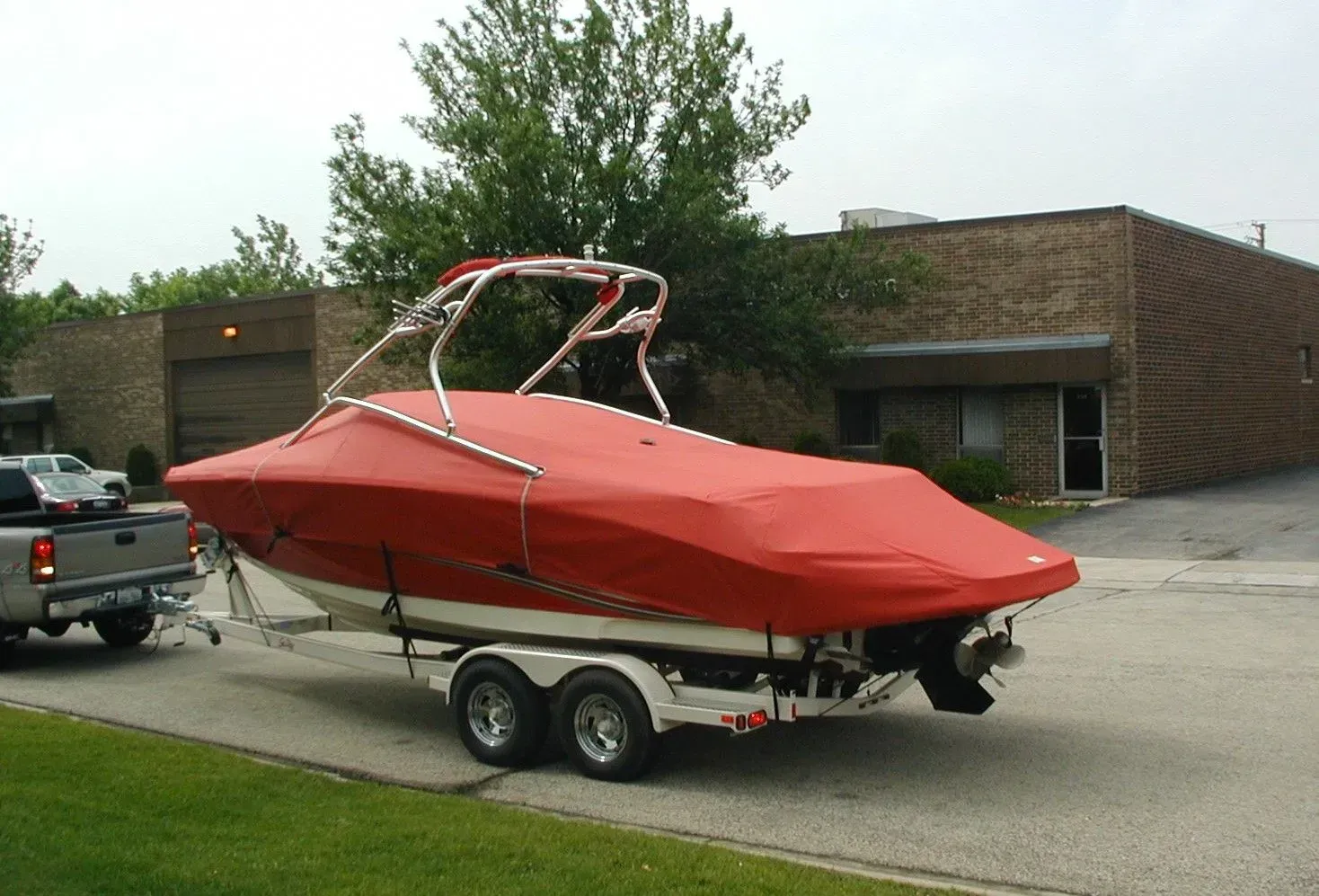 A red boat is on a trailer in front of a building