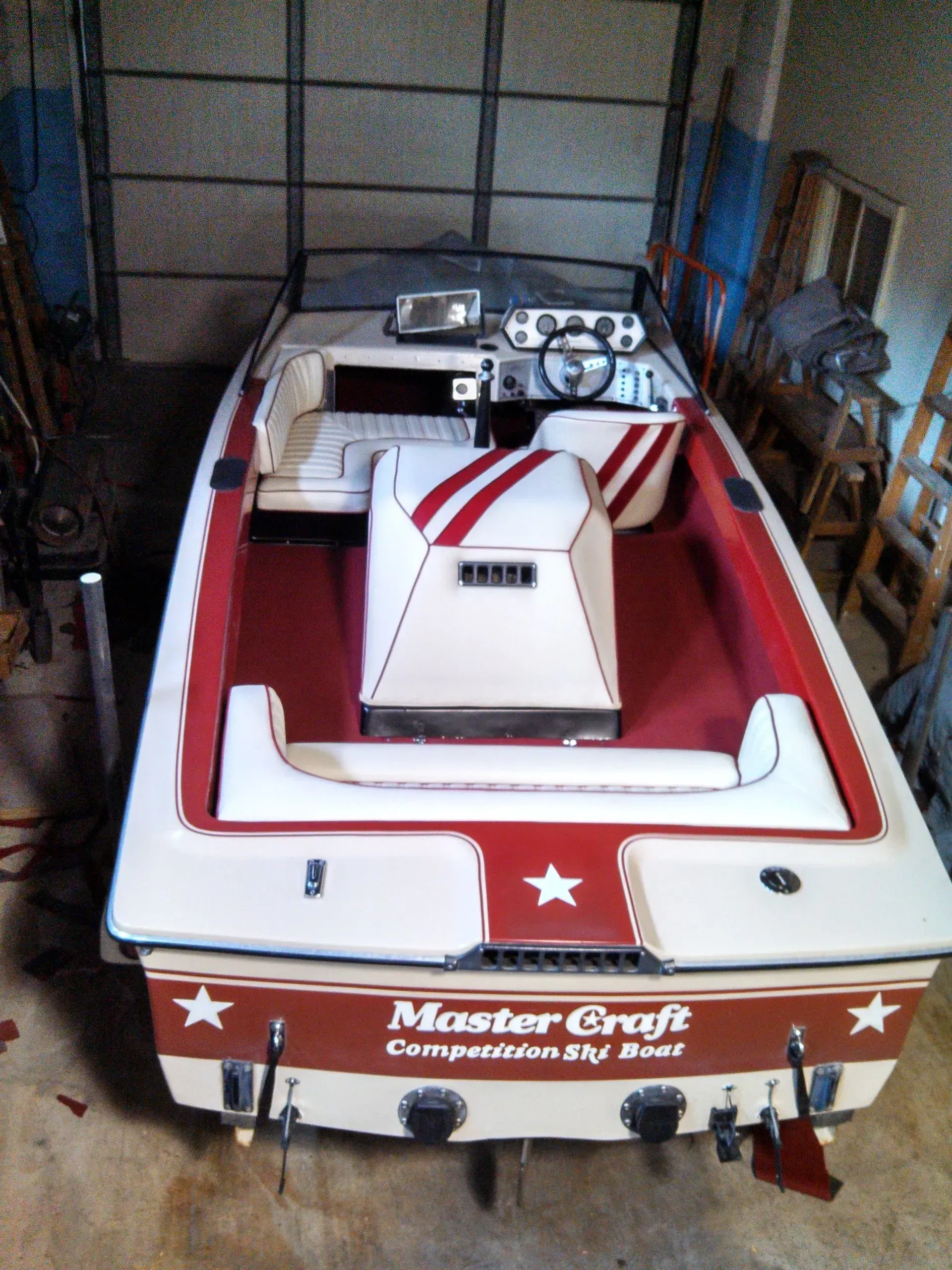 A white and red master craft boat is parked in a garage