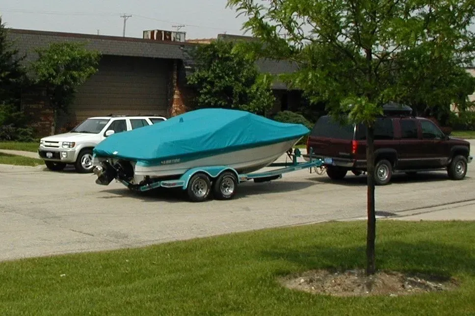 A boat on a trailer with a green cover on it