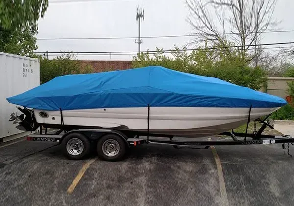 A boat on a trailer with a blue cover on it