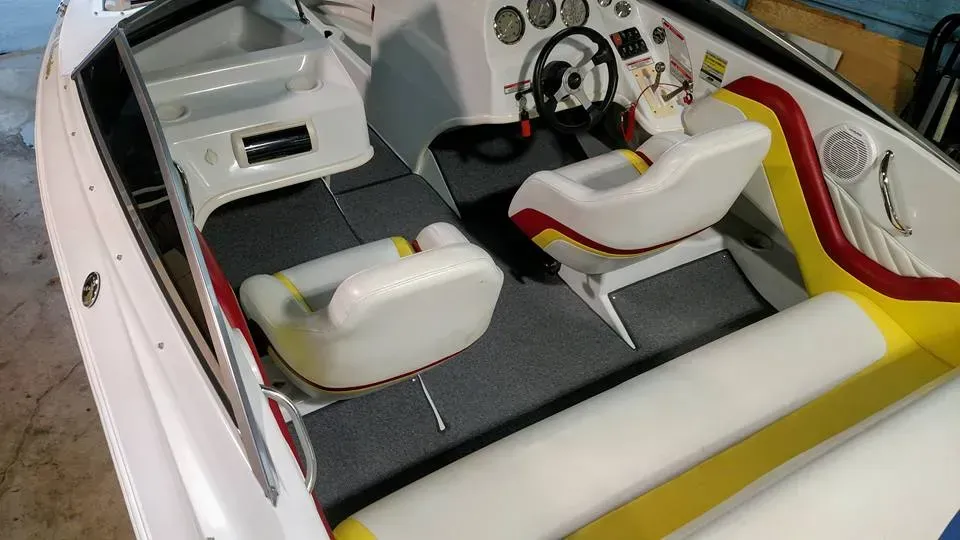 A white boat with yellow and red seats and a steering wheel.