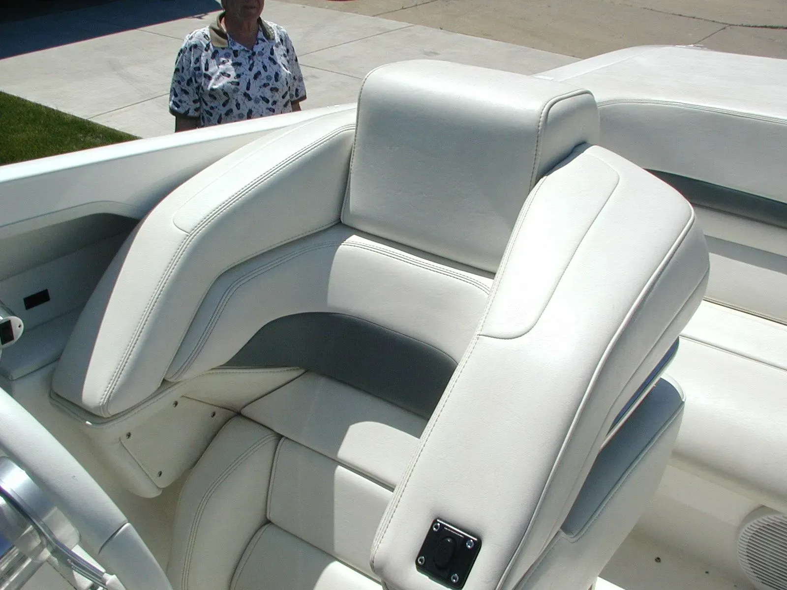 A man is standing next to a boat with white seats