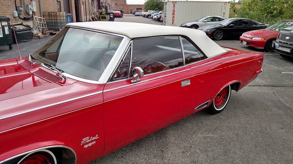 A red car with a white top is parked in a parking lot.