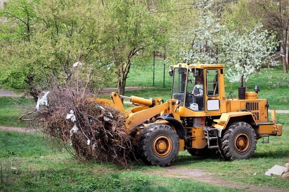 a yellow bulldozer is moving branches.