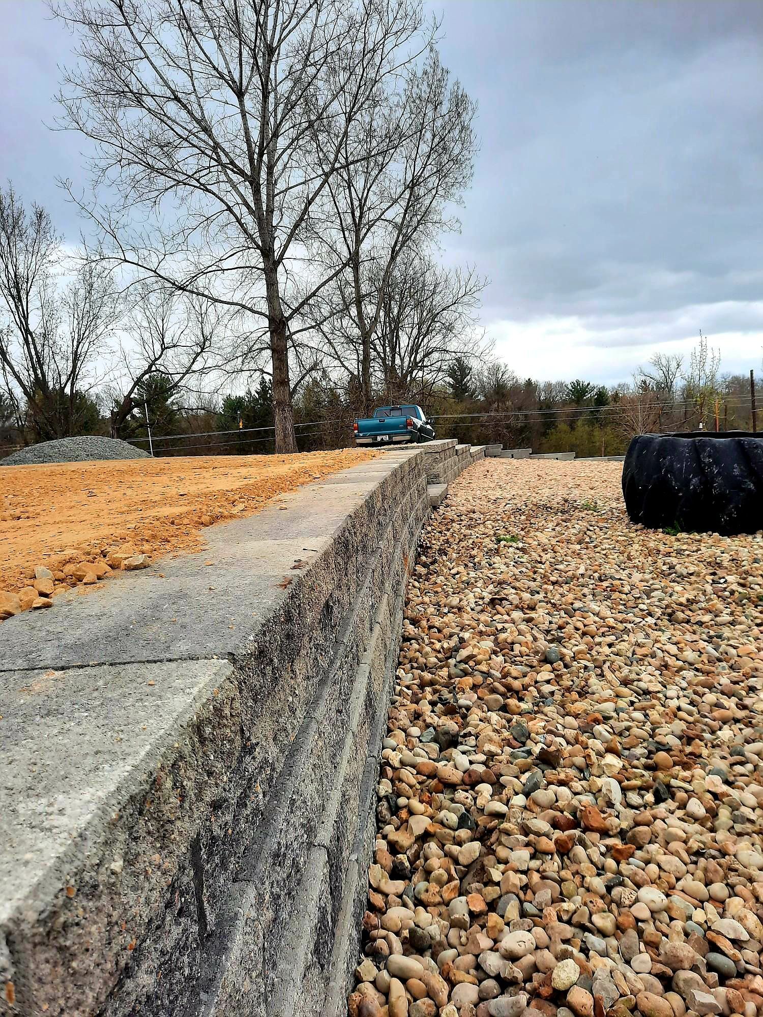 A concrete wall is surrounded by gravel and dirt.
