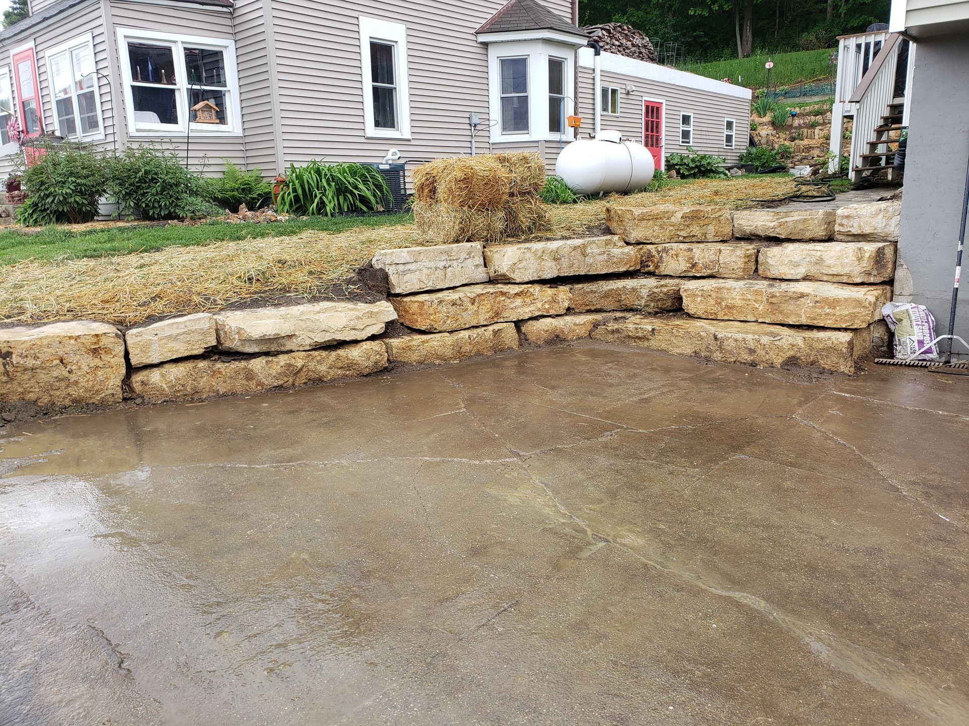 A large stone wall is in front of a house.