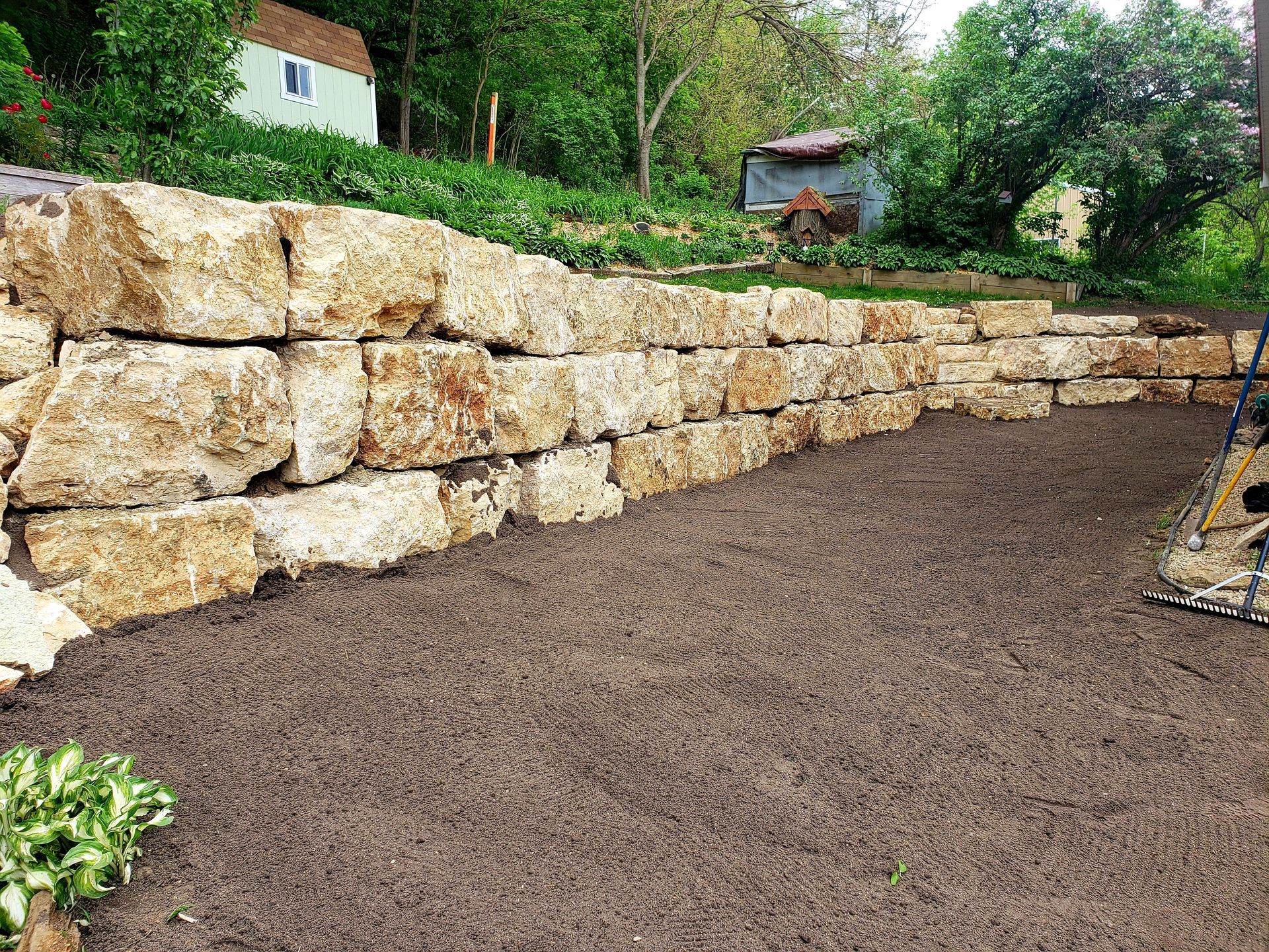 A large stone wall is being built in a backyard.