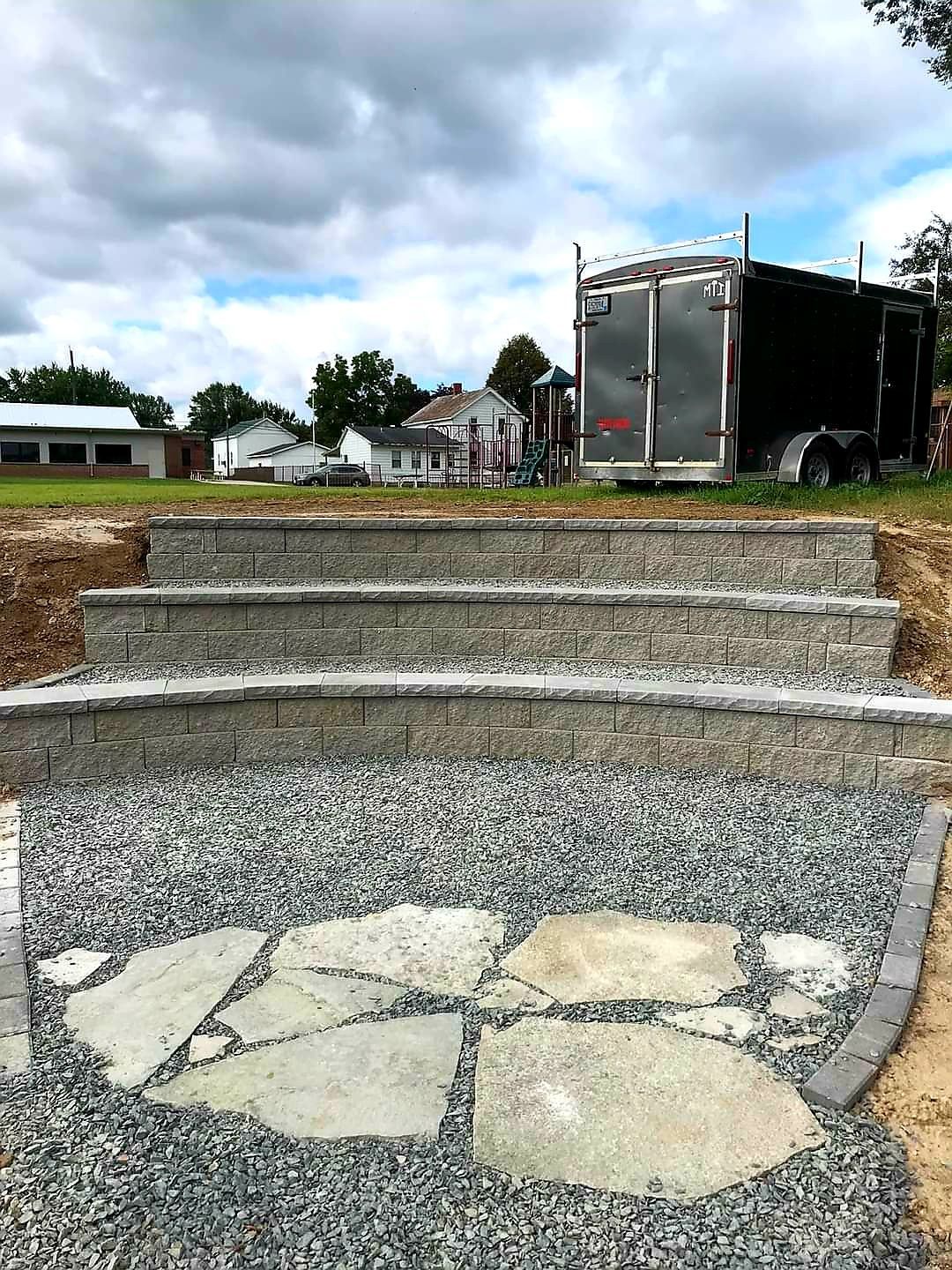 A black trailer is parked next to a set of stairs.